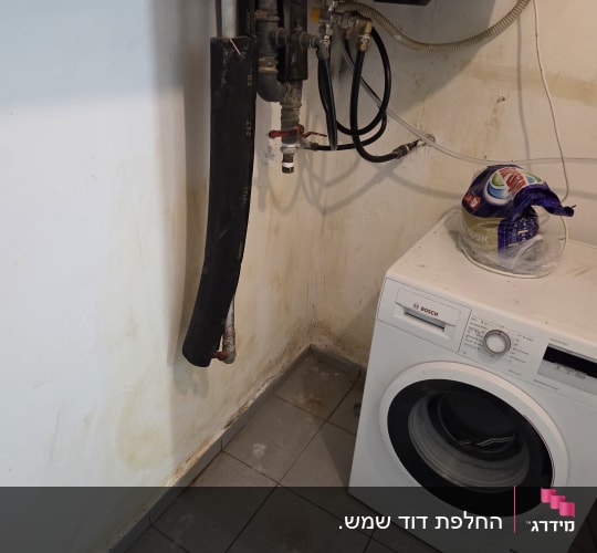 מכונת כביסה עם צינורות וחיבורים על הקיר